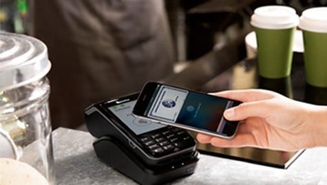 Making payment using smartphone by holding it up to a contactless reader at a cafe. Making payment using smartphone by holding it up to a contactless reader at a cafe.