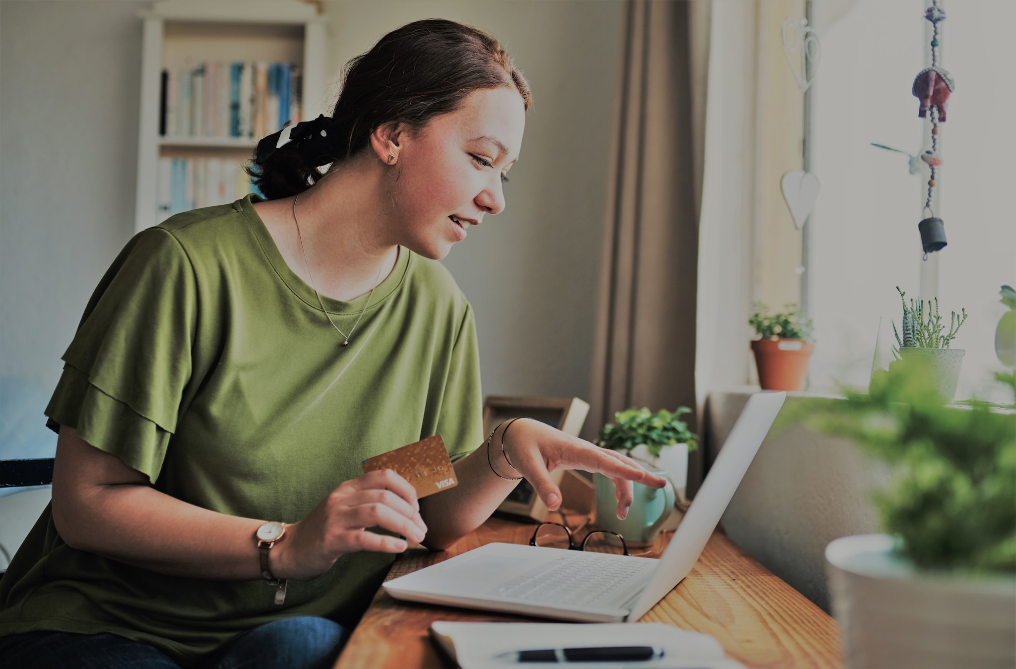 A lady holding an Amex Card checking her laptop. A lady holding an Amex Card checking her laptop.