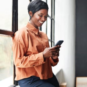 Une femme d’affaires sourit en utilisant son téléphone
