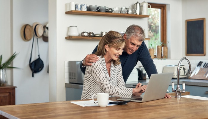 Mature couple going through paperwork and working online with a computer.