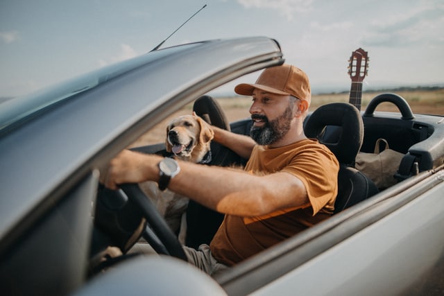 Cash Man having good time with his dog in convertible car.