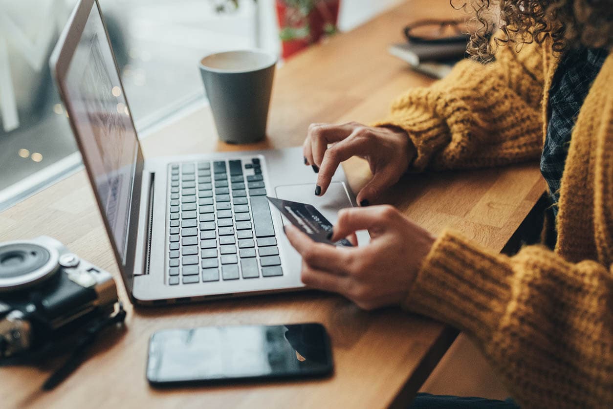 Person using a laptop holding a credit card