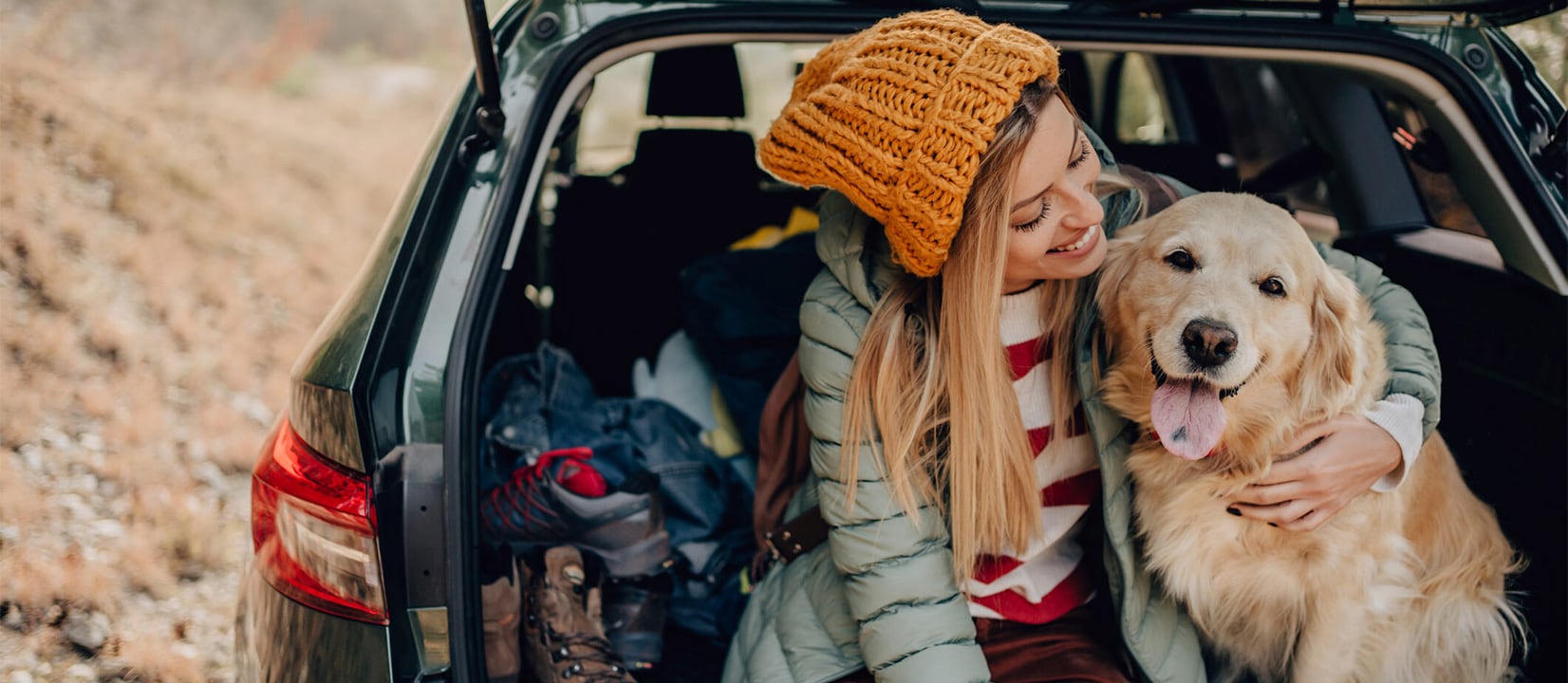 A cheerful woman sitting at the back of a car with a dog. A cheerful woman sitting at the back of a car with a dog.