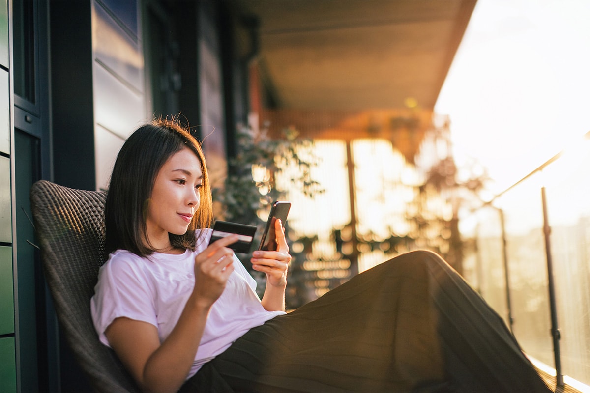Someone holding their credit card while browsing on their phone