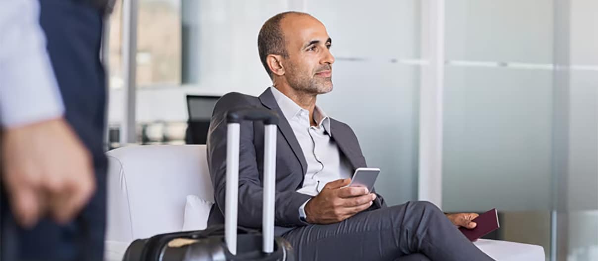 Man is sitting in the chair in the airport and holding the cellphone Man is sitting in the chair in the airport and holding the cellphone