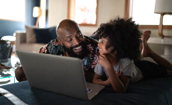 Man and child looking at laptop together Man and child looking at laptop together