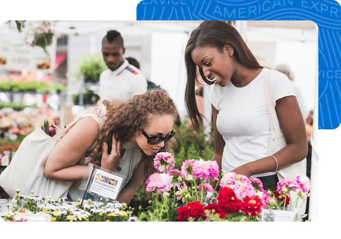 Two women shopping at their local flourist shop. One women is sniffing the vibrant flowers.