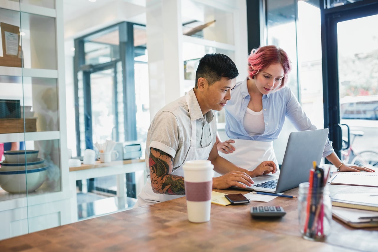 Two business owners sitting at table and looking at laptop